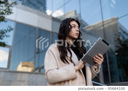 strong successful businesswoman with a tablet in her hands on the background of an office building strong successful businesswoman with a tablet in her hands on the background of an office building 95664100