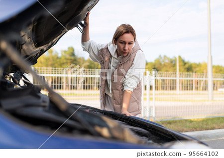 woman In Islam lousy car with the hood up trying to find the cause of the breakdown of the car woman In Islam lousy car with the hood up trying to find the cause of the breakdown of the car 95664102