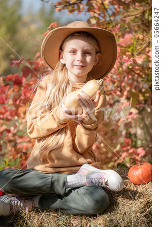 Girl in the hay with pumpkins 95664247