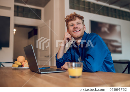 Ginger young man sitting at the table in the kithcen Ginger young man sitting at the table in the kithcen 95664762