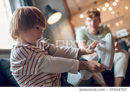 Little boy looking busy while getting on his shoes 95664767