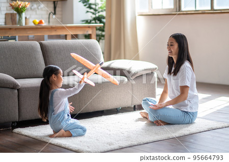 Little girl and her female parent playing on the floor 95664793