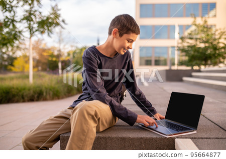 Teen tapping the touchpad on his laptop Teen tapping the touchpad on his laptop 95664877