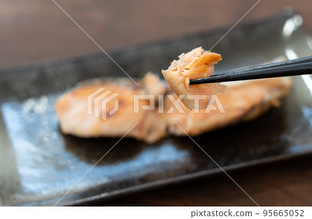 He is picking up grilled salmon from Hokkaido with chopsticks. 95665052