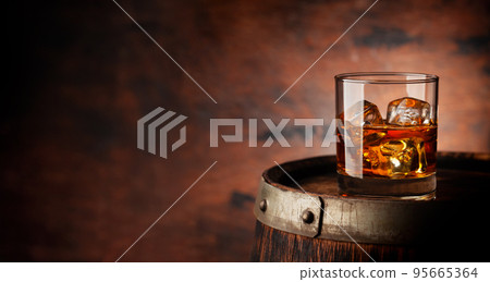 Glass of whiskey with ice cubes on the old barrel 95665364