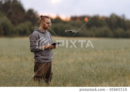 Man controlling a drone with a remote control Man controlling a drone with a remote control 95665519