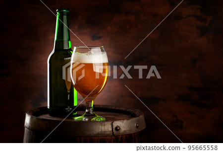 Beer glass and bottle on wooden barrel 95665558
