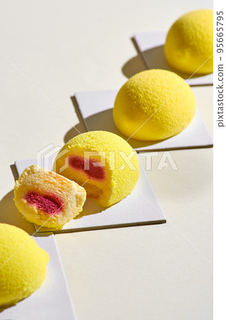 Modern European mini-mousse desserts covered in the form of a lemon on a light background. Top view 95665795