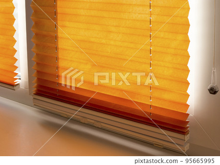 Pleated blinds with orange folded fabric on the window close up. Cordless bottom up top down pleated shade with white lower bar. 95665995