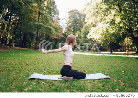 Girl doing yoga in the park on the mat. Yoga exercise outdoor.. Girl doing yoga in the park on the mat. Yoga exercise outdoor.. 95666270