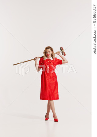 Portrait of beautiful woman in styles red dress posing with mop isolated over white background 95666317