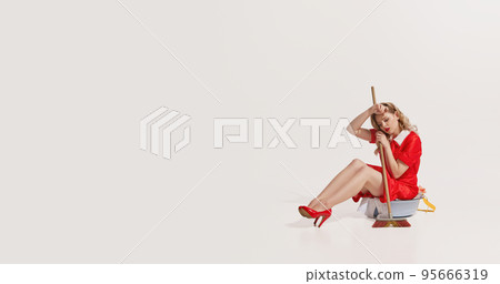 Portrait of elegant woman sitting in bowl with clothes and holding mop isolated on white background. Tired and exhausted 95666319