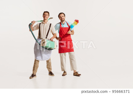 Portrait of two men in aprons with vacuum cleaner and pipidastre isolated over white background. Male cleaning service Portrait of two men in aprons with vacuum cleaner and pipidastre isolated over white background. Male cleaning service 95666371
