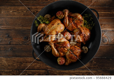 Roasted whole chicken with backed apples and garlic  in iron cast pan 95666429