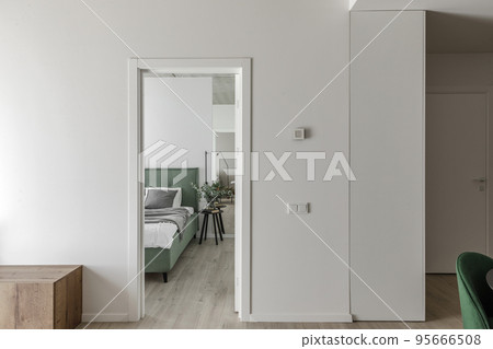 Modern minimalistic bedroom interior design with light green bed, eucalyptus in glass vase. Scandinavian style.  Aesthetic simple interior design concept. 95666508