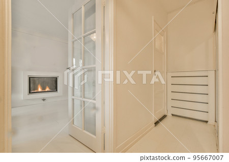 Narrow corridor with white walls and doors leading to spacious room with windows and parquet floor in modern apartment Narrow corridor with white walls and doors leading to spacious room with windows and parquet floor in modern apartment 95667007