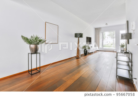 Interior of living room with comfortable sofa and TV against windows in contemporary apartment 95667058
