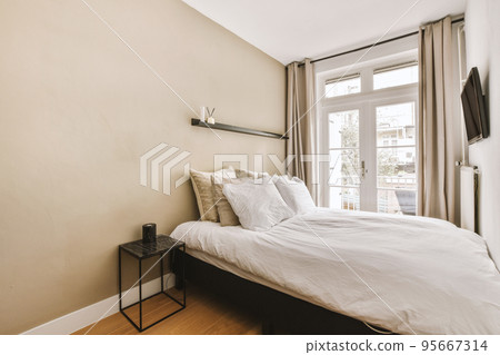 Home interior design of bedroom with bed and wooden wardrobe placed in corner near window in modern apartment 95667314