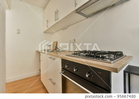 Interior of light kitchen room with balcony doors in contemporary apartment at daytime 95667480
