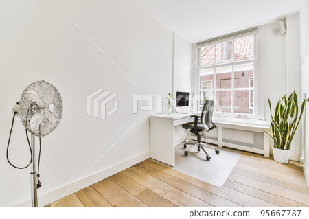 Comfortable chair placed near table with computer monitors against blank whiteboard and mirror in light home office in contemporary flat 95667787