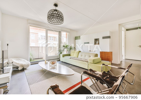 Comfortable sofa with cushions placed against light wall with TV and decorations in modern loving room Comfortable sofa with cushions placed against light wall with TV and decorations in modern loving room 95667906
