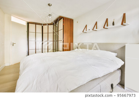 Home interior design of bedroom with bed and wooden wardrobe placed in corner near window in modern apartment Home interior design of bedroom with bed and wooden wardrobe placed in corner near window in modern apartment 95667973