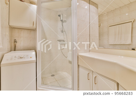 Flush toilet located between sink and shower in small tiled bathroom of contemporary apartment Flush toilet located between sink and shower in small tiled bathroom of contemporary apartment 95668283