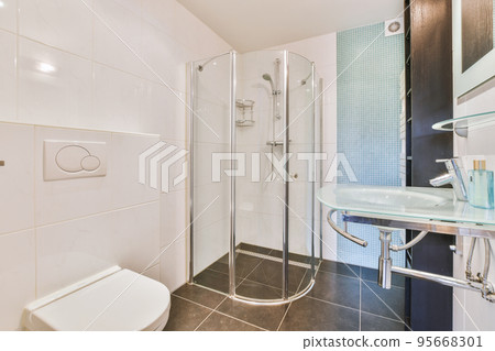 Flush toilet located between sink and shower in small tiled bathroom of contemporary apartment Flush toilet located between sink and shower in small tiled bathroom of contemporary apartment 95668301