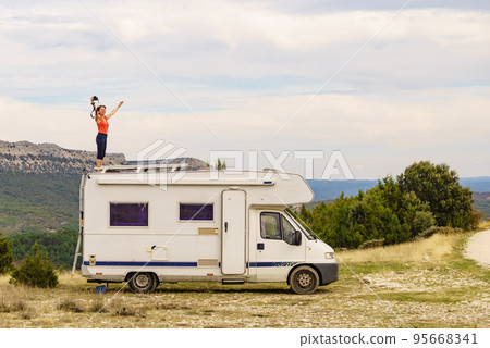 Woman traveling with caravan, taking photo from rv roof 95668341