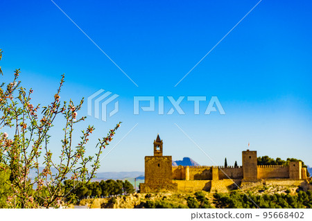 Spring tree and Alcazaba fortress in Antequera, Spain. 95668402
