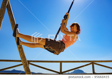 Adult woman having fun on zipline Adult woman having fun on zipline 95668435