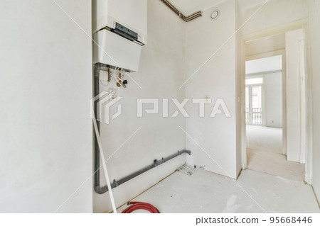 Boiler room of an apartment building with pipes and metering devices. A long room with engineering communications in the modern apartment Boiler room of an apartment building with pipes and metering devices. A long room with engineering communications in the modern apartment 95668446
