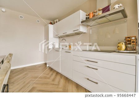 Table with chairs and flowers located near lounge area and kitchen in spacious room of contemporary apartment Table with chairs and flowers located near lounge area and kitchen in spacious room of contemporary apartment 95668447