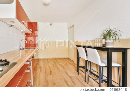 Home interior design of modern loft apartment with open kitchen in minimalist style and spacious dining zone with table and chairs Home interior design of modern loft apartment with open kitchen in minimalist style and spacious dining zone with table and chairs 95668448