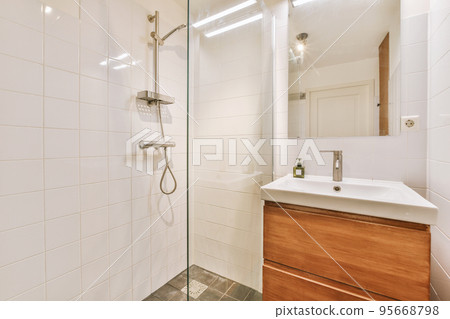 Sinks with mirrors and shower box with glass door in modern bathroom with white tiled walls 95668798