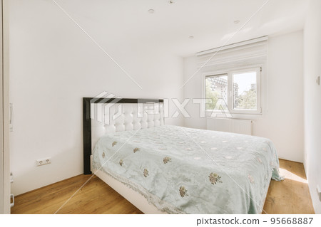 Home interior design of bedroom with bed and wooden wardrobe placed in corner near window in modern apartment 95668887