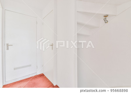 White hallway with wooden stairway leading to second floor of modern luxury apartment with minimalist interior design 95668898