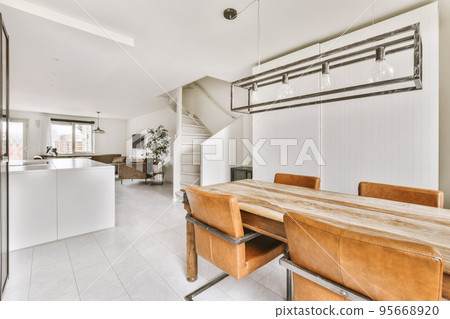 Contemporary open plan kitchen with dining table set and gray sofa in light spacious room 95668920