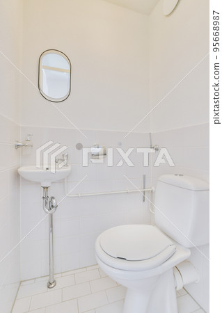 Interior of narrow restroom with sink and wall hung toilet with white walls and checkered floor Interior of narrow restroom with sink and wall hung toilet with white walls and checkered floor 95668987