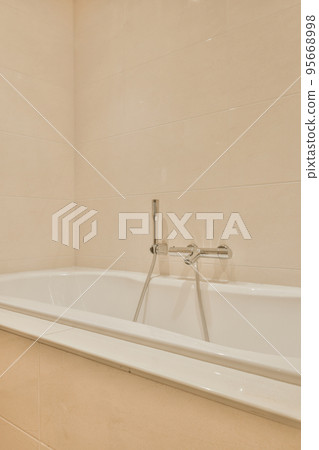 Modern home interior design of white bathroom with open bathtub and shower separated from toilet by partition wall Modern home interior design of white bathroom with open bathtub and shower separated from toilet by partition wall 95668998