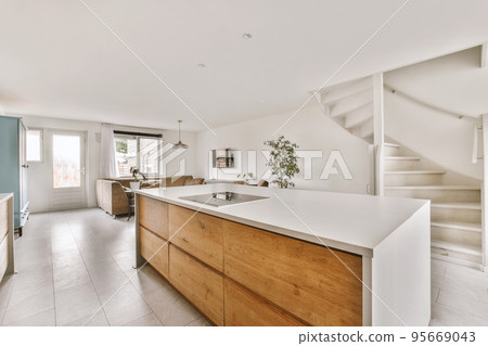 Contemporary open plan kitchen with dining table set and gray sofa in light spacious room 95669043