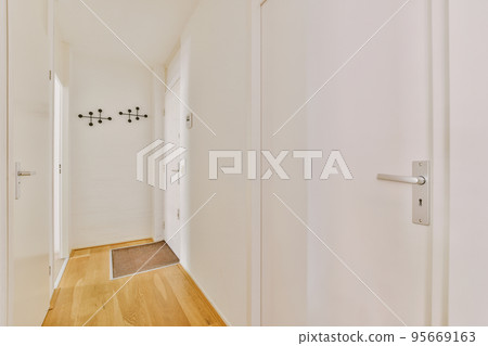 Light narrow hallway with many doors in white walls and glowing lamp over lumber floor 95669163