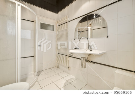 Flush toilet located between sink and shower in small tiled bathroom of contemporary apartment Flush toilet located between sink and shower in small tiled bathroom of contemporary apartment 95669166