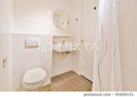 Bathroom with white tiled walls and open shower near sink and toilet in light Bathroom with white tiled walls and open shower near sink and toilet in light 95669191