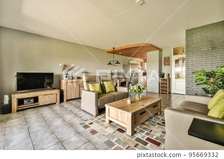 Table with chairs and flowers located near lounge area and kitchen in spacious room of contemporary apartment Table with chairs and flowers located near lounge area and kitchen in spacious room of contemporary apartment 95669332