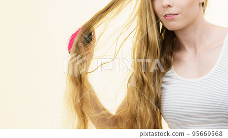 Blonde girl brushing her long hair Blonde girl brushing her long hair 95669568