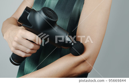 sportsman massaging his arm with a massage gun 95669844