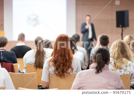 Speaker giving a talk in conference hall at business event. Rear view of unrecognizable people in audience at the conference hall. Business and entrepreneurship concept. 95670175