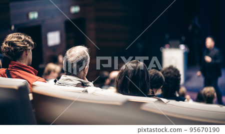 Speaker giving a talk in conference hall at business event. Rear view of unrecognizable people in audience at the conference hall. Business and entrepreneurship concept. 95670190