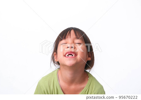 Portrait of an Asian girl with broken upper baby teeth and first permanent teeth. Friendly little girl showing her broken teeth isolated on white background. 95670222